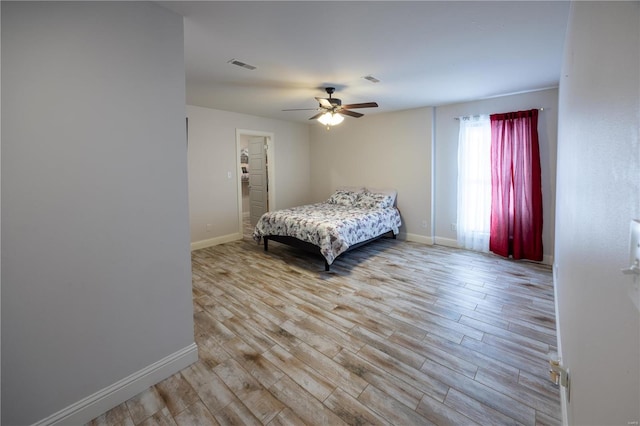 bedroom with ceiling fan, light wood-type flooring, and a spacious closet