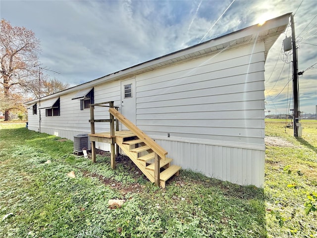 view of property exterior with central air condition unit and a yard