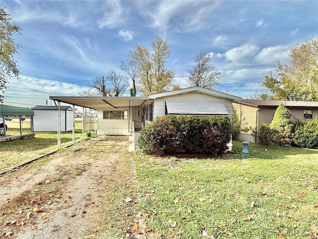 manufactured / mobile home with a front lawn, a storage unit, and a carport