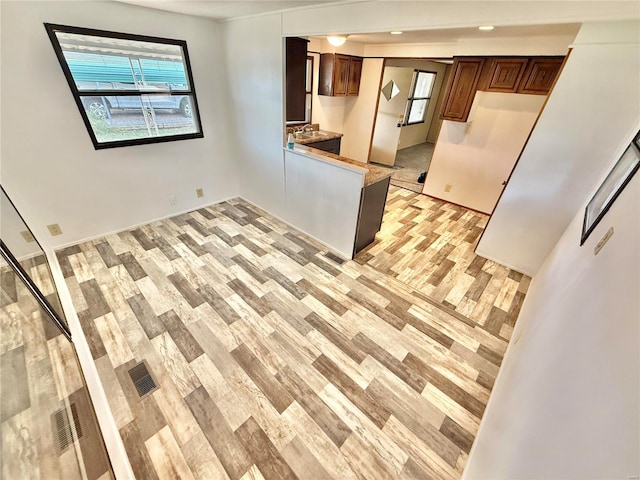 kitchen with kitchen peninsula, sink, and light hardwood / wood-style floors