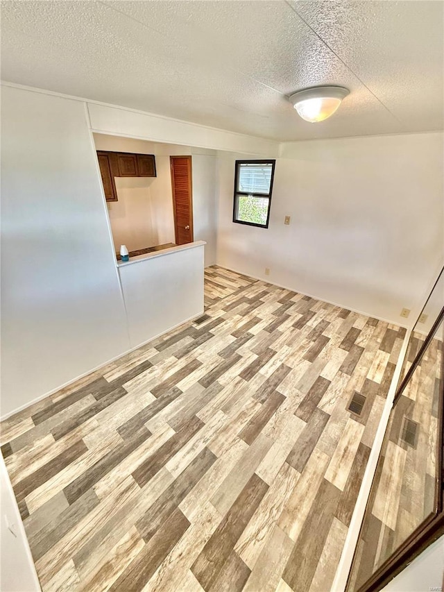 unfurnished room with light wood-type flooring and a textured ceiling