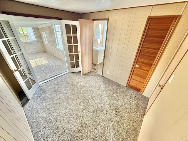 doorway featuring carpet floors, french doors, and wood walls