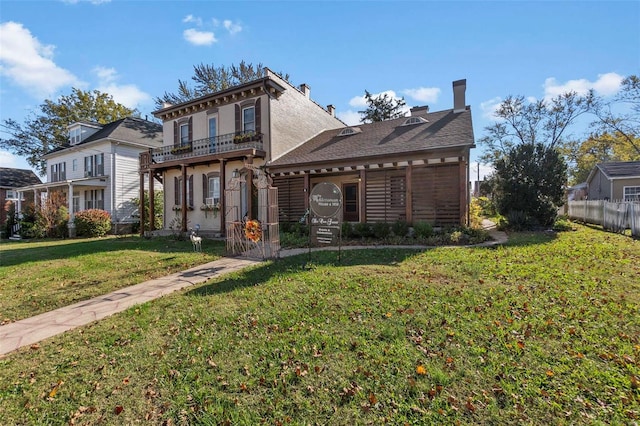 rear view of property with a yard and a balcony