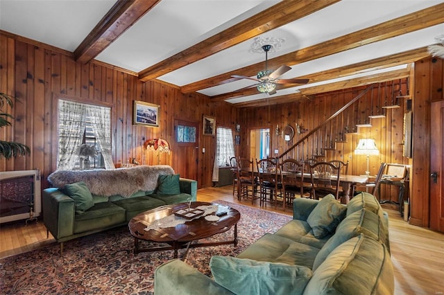 living room featuring beam ceiling, wood walls, ceiling fan, and light hardwood / wood-style floors