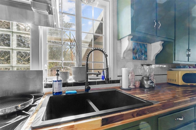 kitchen featuring plenty of natural light, butcher block counters, sink, and tasteful backsplash