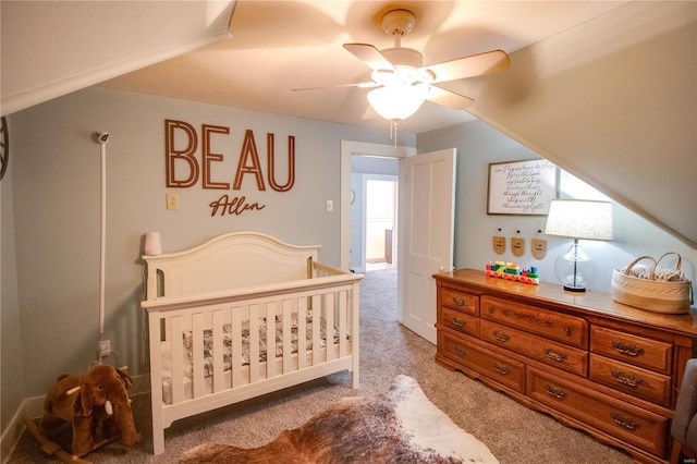 bedroom with ceiling fan, a nursery area, and light colored carpet