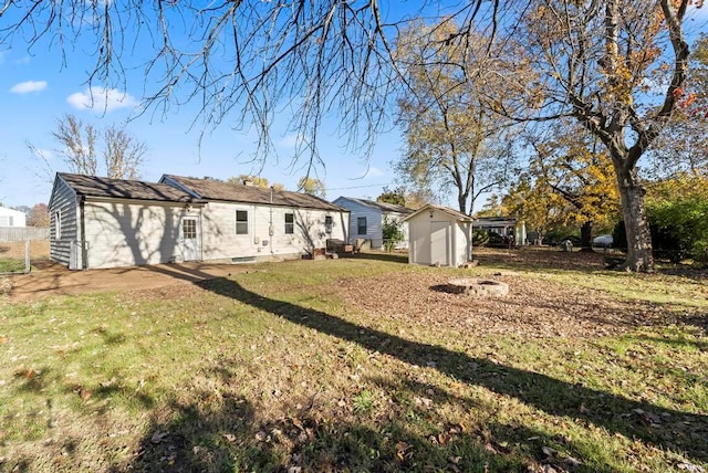 back of property with a lawn and a storage shed