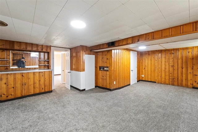 basement featuring wood walls and light carpet