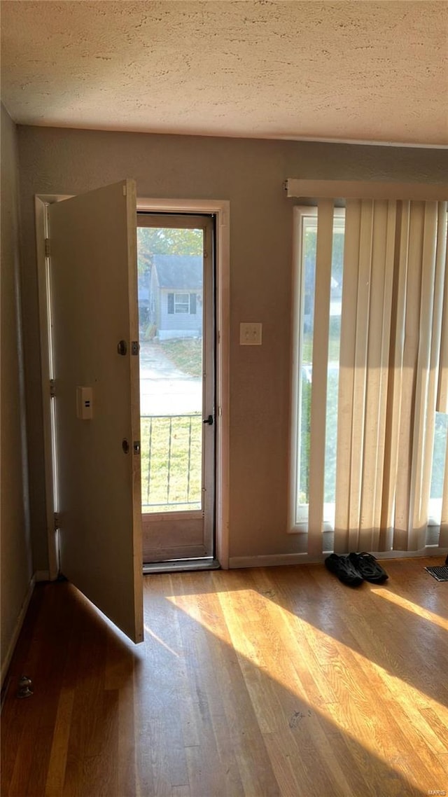 doorway to outside with hardwood / wood-style floors and a textured ceiling