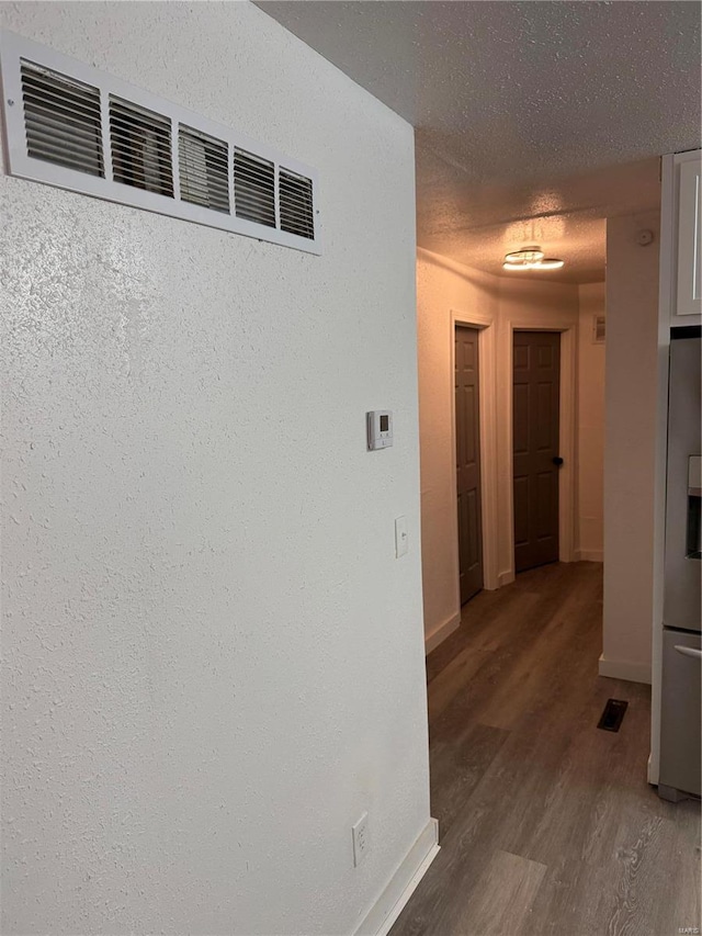 corridor featuring dark hardwood / wood-style flooring and a textured ceiling