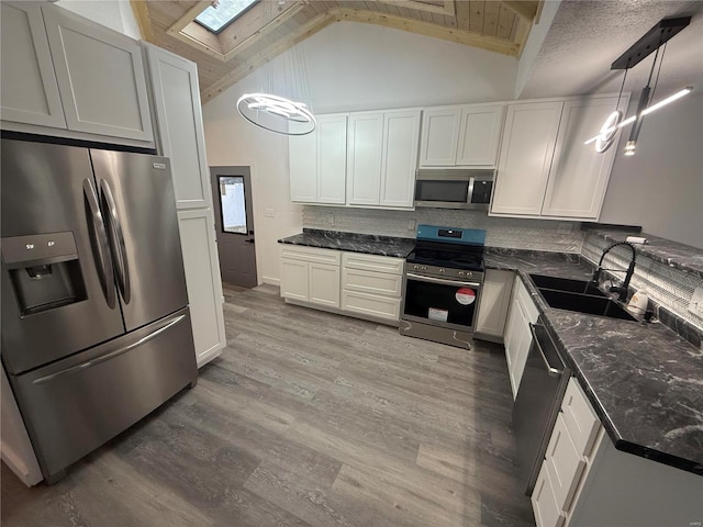 kitchen featuring pendant lighting, sink, hardwood / wood-style flooring, appliances with stainless steel finishes, and white cabinetry