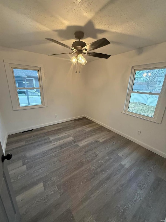 empty room featuring ceiling fan, dark wood-type flooring, and a textured ceiling