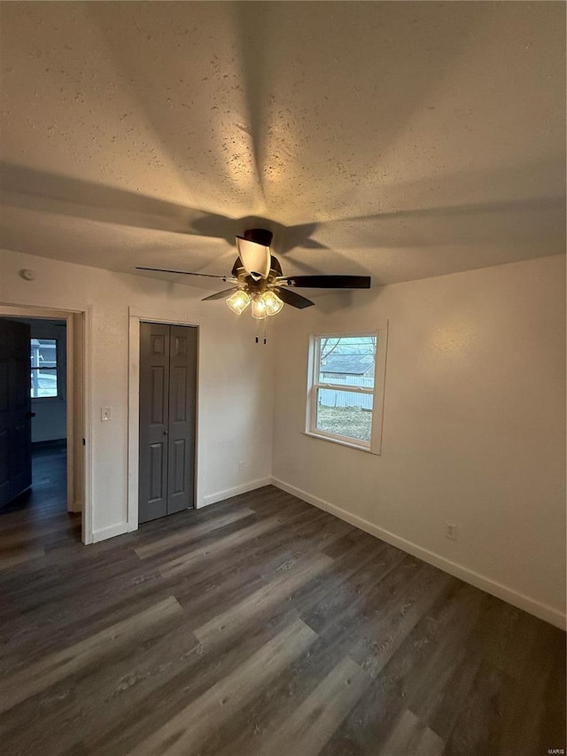 unfurnished bedroom featuring ceiling fan, dark hardwood / wood-style flooring, and a textured ceiling