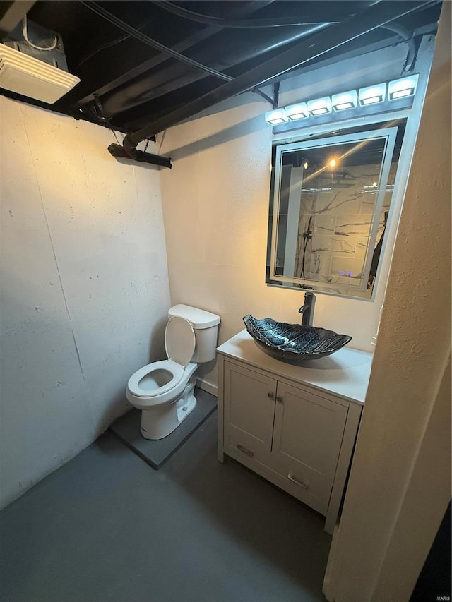 bathroom featuring vanity, concrete flooring, and toilet