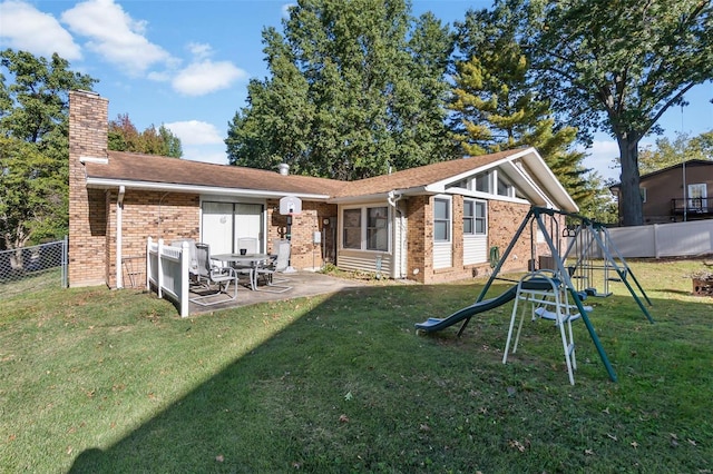 rear view of property featuring a playground, a yard, and a patio area