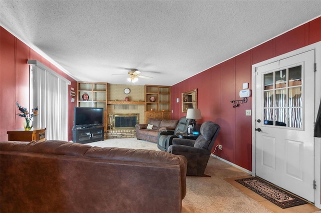 carpeted living room with ceiling fan, built in features, a textured ceiling, and a fireplace