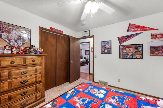 bedroom featuring a textured ceiling, light colored carpet, ceiling fan, and a closet