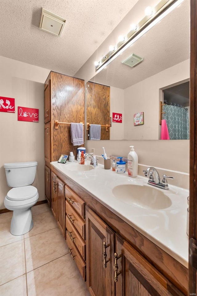 bathroom with toilet, vanity, a textured ceiling, and tile patterned floors