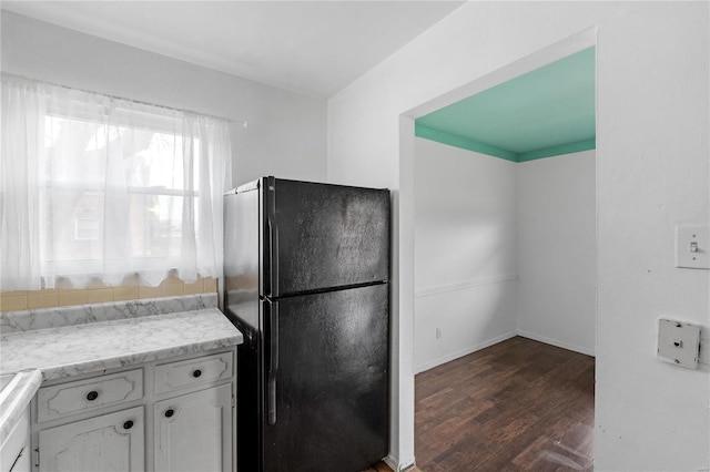 kitchen featuring white cabinets, black refrigerator, and dark hardwood / wood-style flooring