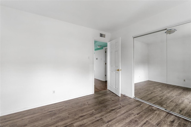 unfurnished bedroom featuring dark hardwood / wood-style floors and a closet