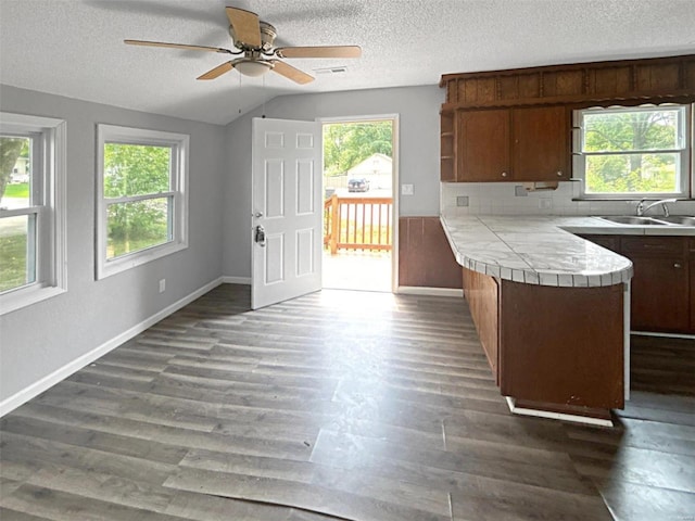 kitchen with sink, dark hardwood / wood-style flooring, tile counters, kitchen peninsula, and decorative backsplash