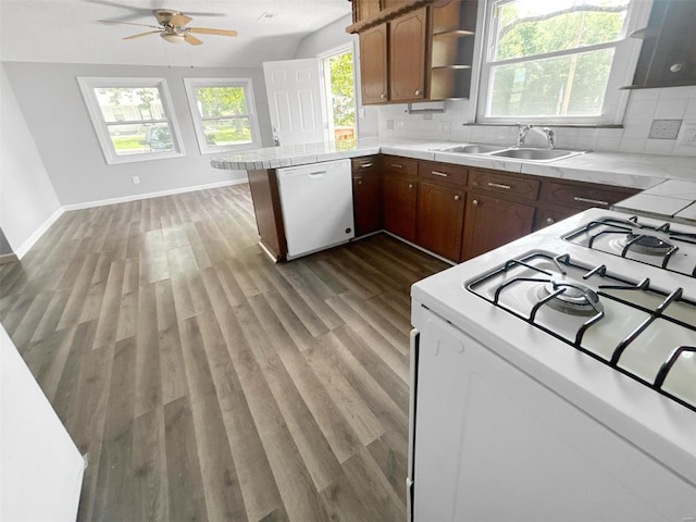 kitchen featuring sink, white appliances, tasteful backsplash, dark hardwood / wood-style flooring, and kitchen peninsula