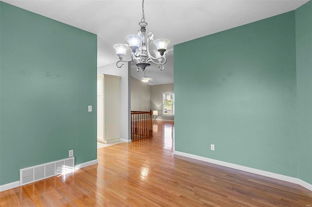 unfurnished room featuring a notable chandelier and light wood-type flooring