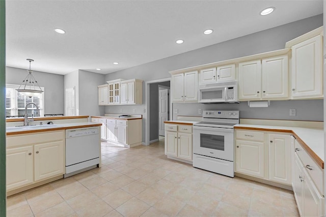 kitchen with hanging light fixtures, white appliances, cream cabinets, and sink