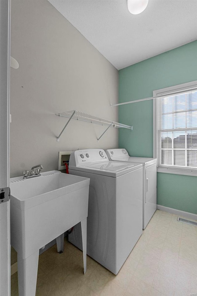 laundry room with washer and clothes dryer, sink, and a textured ceiling