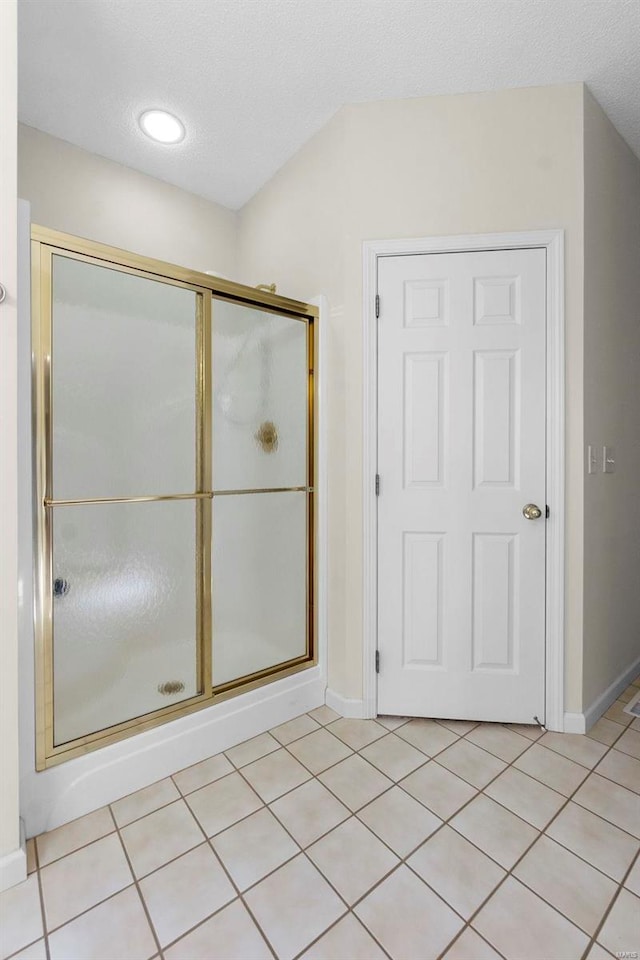 bathroom with a textured ceiling, an enclosed shower, and tile patterned floors