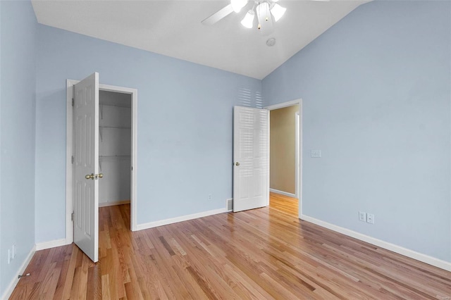 unfurnished bedroom featuring lofted ceiling, a walk in closet, ceiling fan, light hardwood / wood-style floors, and a closet