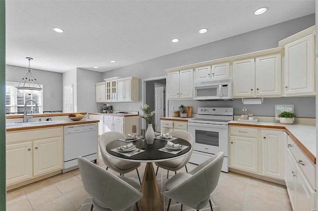 kitchen featuring pendant lighting, white appliances, light tile patterned flooring, and sink