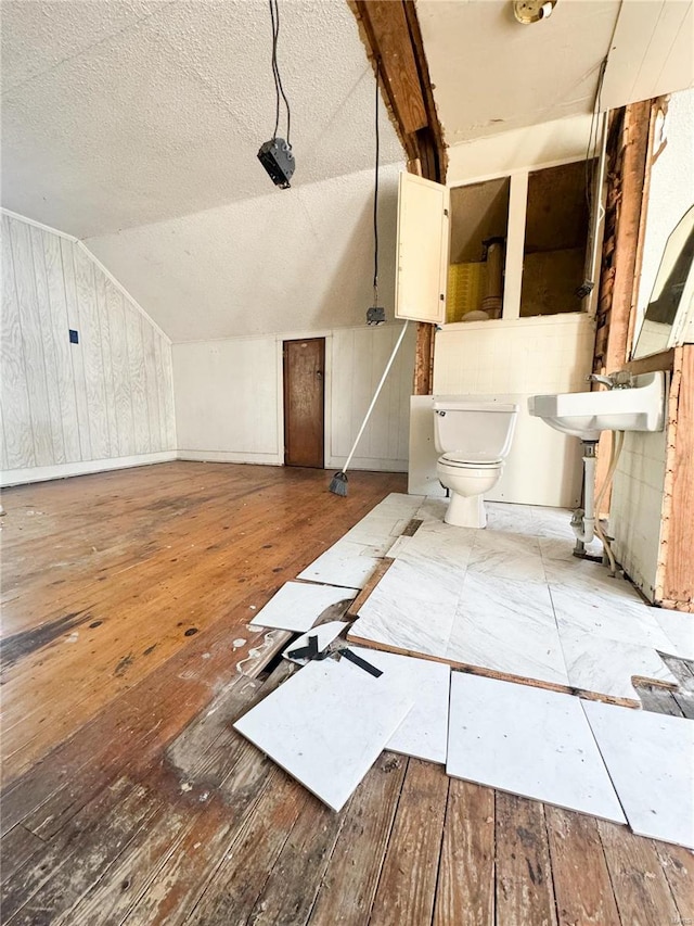 bathroom with hardwood / wood-style floors, toilet, and vaulted ceiling