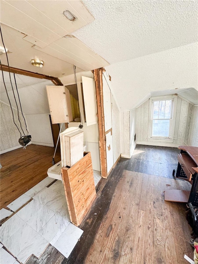 additional living space featuring hardwood / wood-style flooring, a textured ceiling, and lofted ceiling