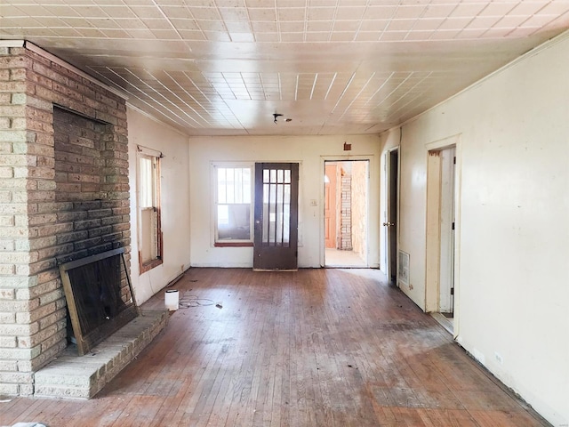 unfurnished living room with hardwood / wood-style flooring and a brick fireplace