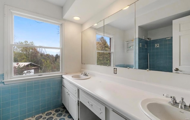 bathroom with tile walls, a tile shower, vanity, and tile patterned floors