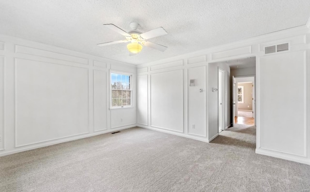 spare room featuring a textured ceiling, light colored carpet, and ceiling fan