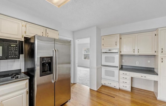 kitchen featuring light wood-type flooring, black appliances, a textured ceiling, and backsplash