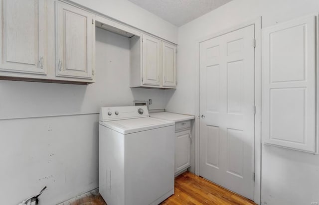 washroom featuring light wood-type flooring, cabinets, a textured ceiling, and washer / dryer