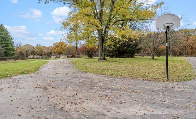 view of property's community featuring a lawn and basketball hoop