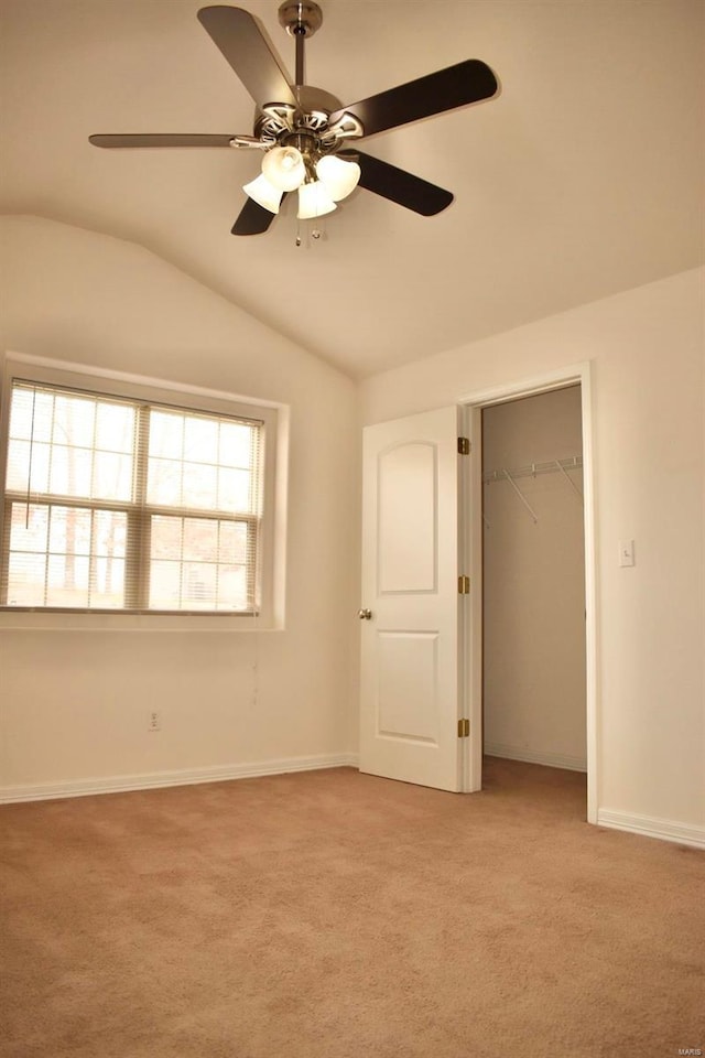 unfurnished bedroom featuring ceiling fan, vaulted ceiling, light colored carpet, and a closet