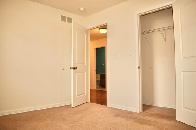 unfurnished bedroom featuring light carpet and a closet