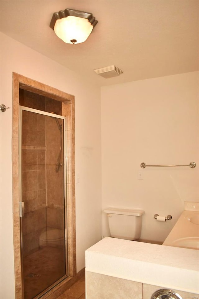 bathroom with tile patterned flooring, toilet, and walk in shower