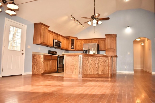 kitchen with appliances with stainless steel finishes, high vaulted ceiling, and light hardwood / wood-style flooring