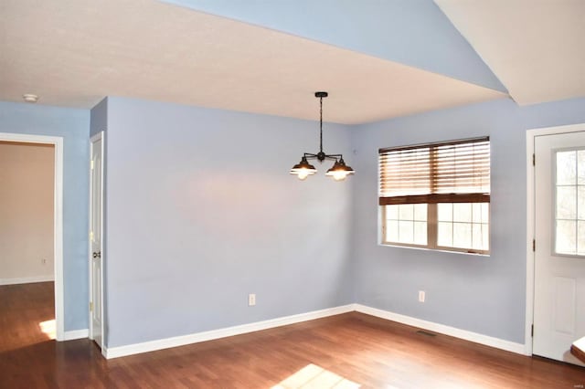 unfurnished dining area with lofted ceiling, dark wood-type flooring, and a notable chandelier