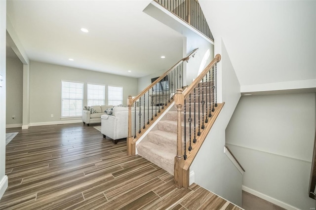 stairs with baseboards, wood finished floors, and recessed lighting