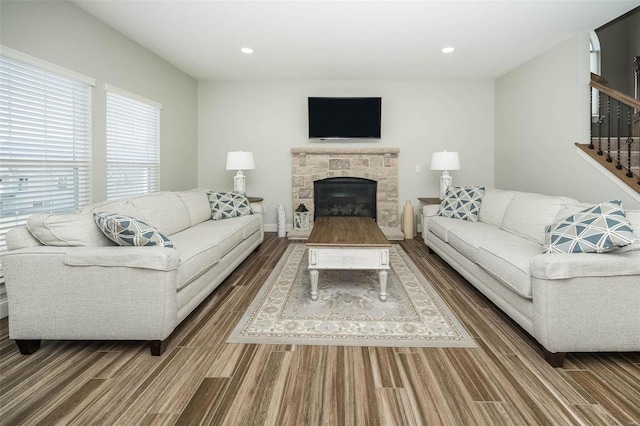 living room with a stone fireplace, stairway, wood finished floors, and recessed lighting