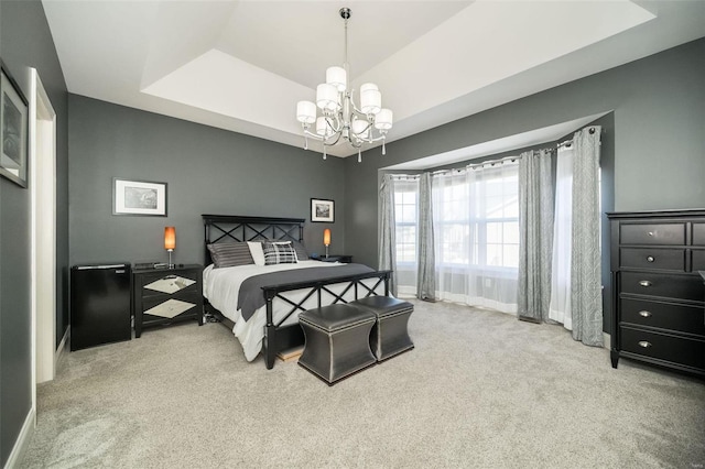 bedroom with an inviting chandelier, carpet, a tray ceiling, and baseboards