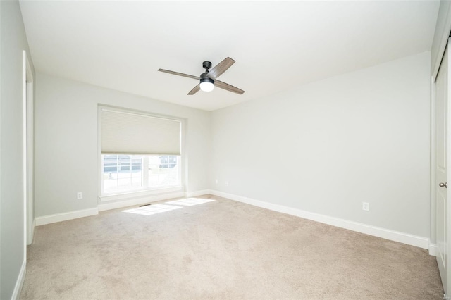 carpeted empty room with ceiling fan and baseboards