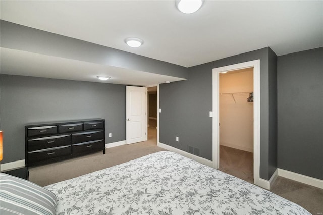 carpeted bedroom with a closet, visible vents, a spacious closet, and baseboards